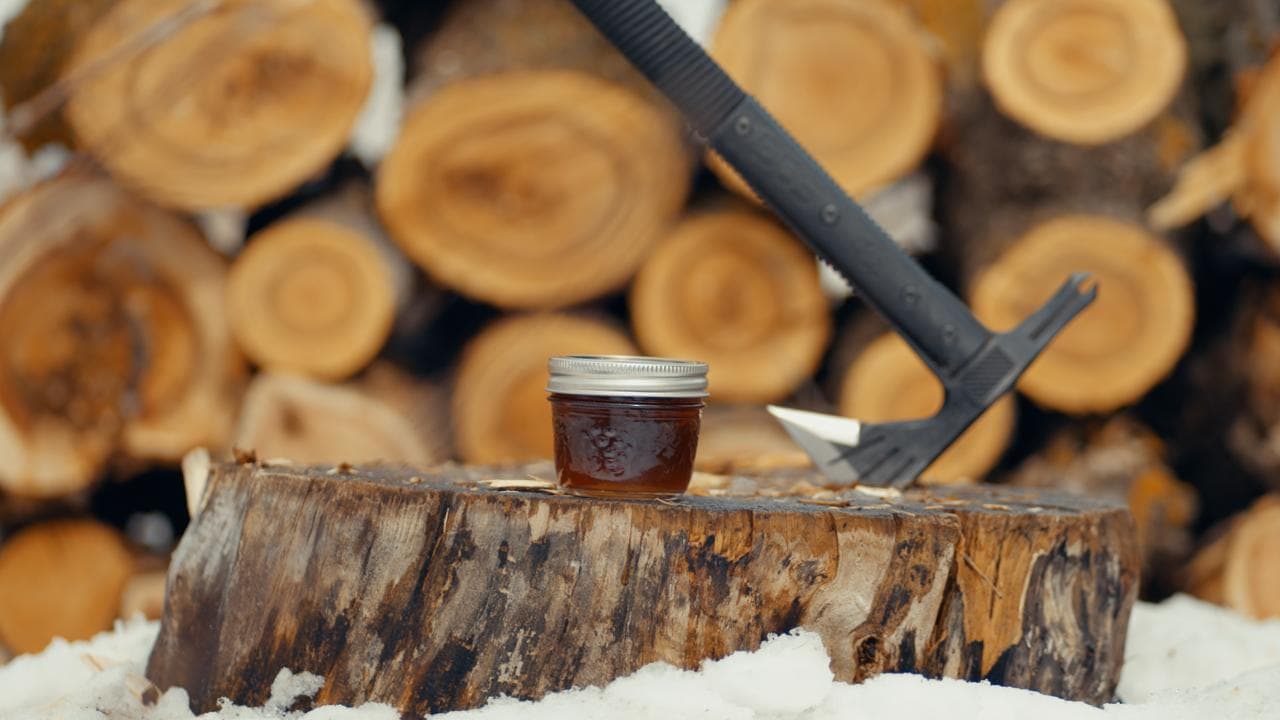 A jar of maple syrup on a stump in the sugarbush